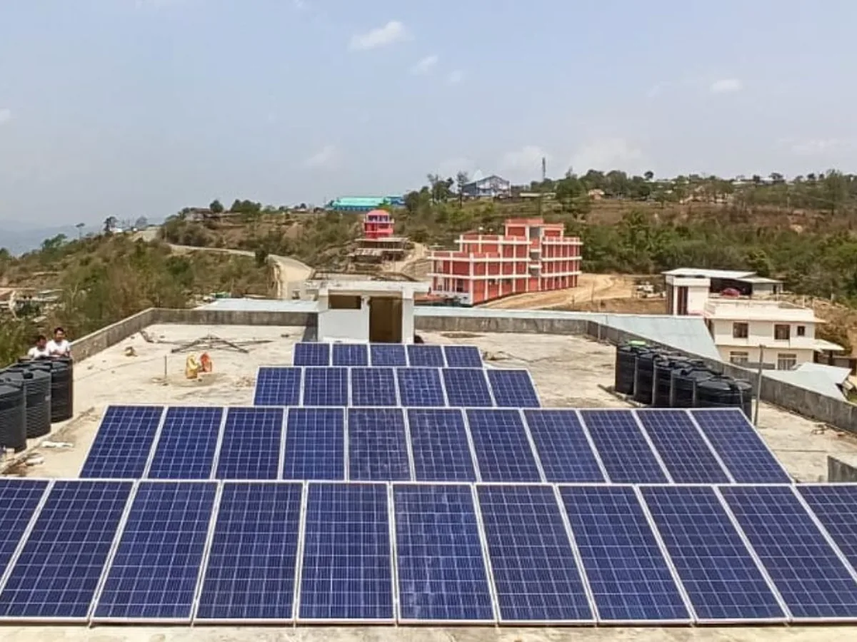 A large rooftop solar array alongside black water storage tanks on a hillside in the North East