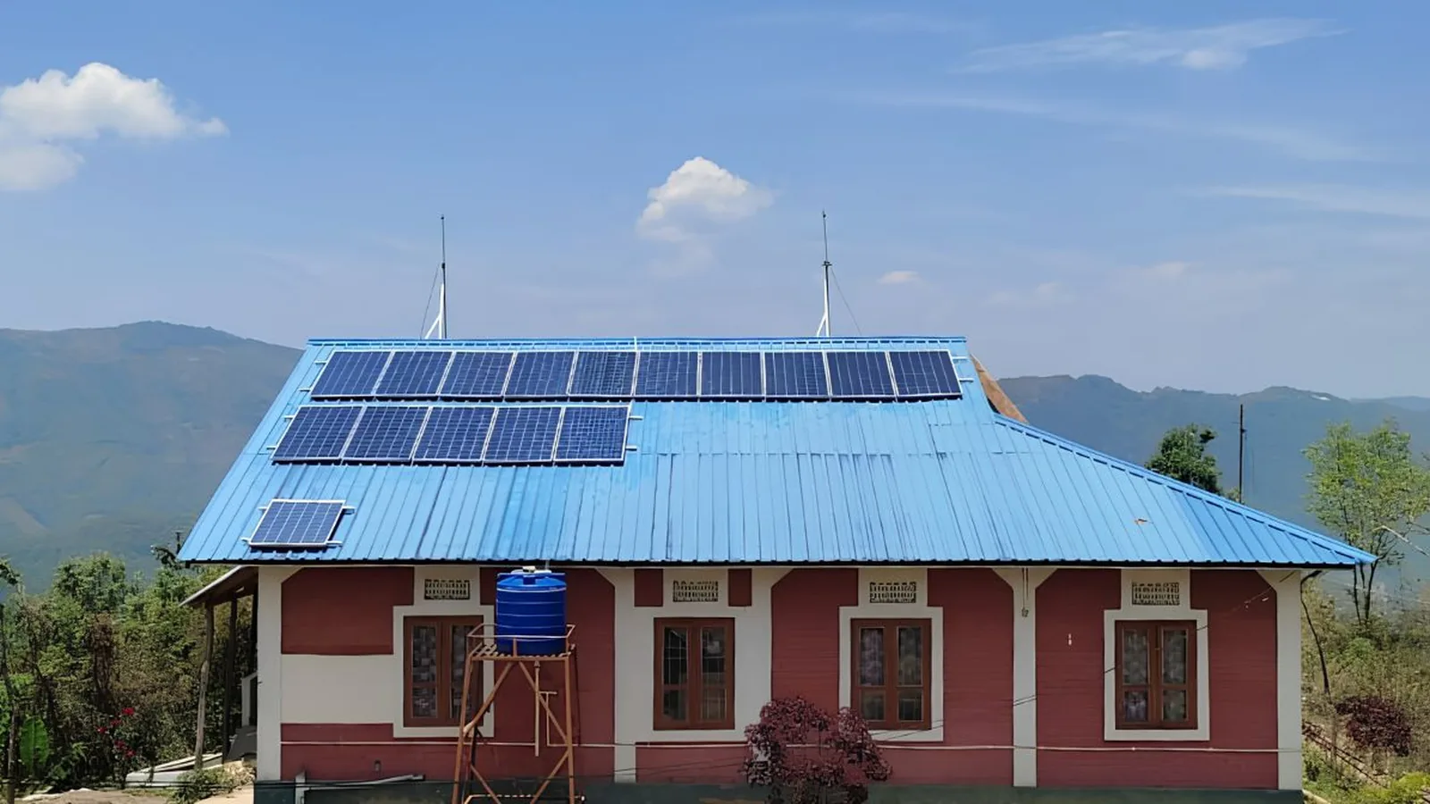 A rural health centre with two rows of solar panels and lightning arrestors on its roof