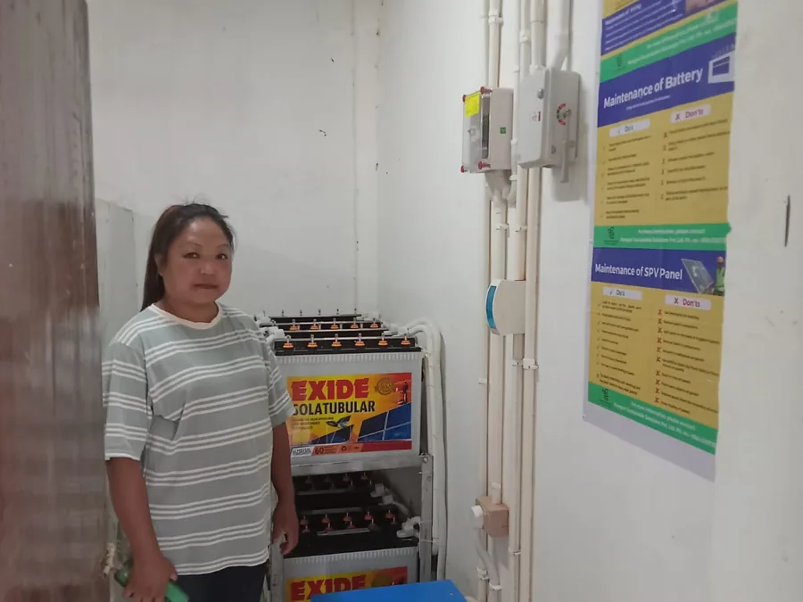 Health centre staff member beside the battery bank powering the facility