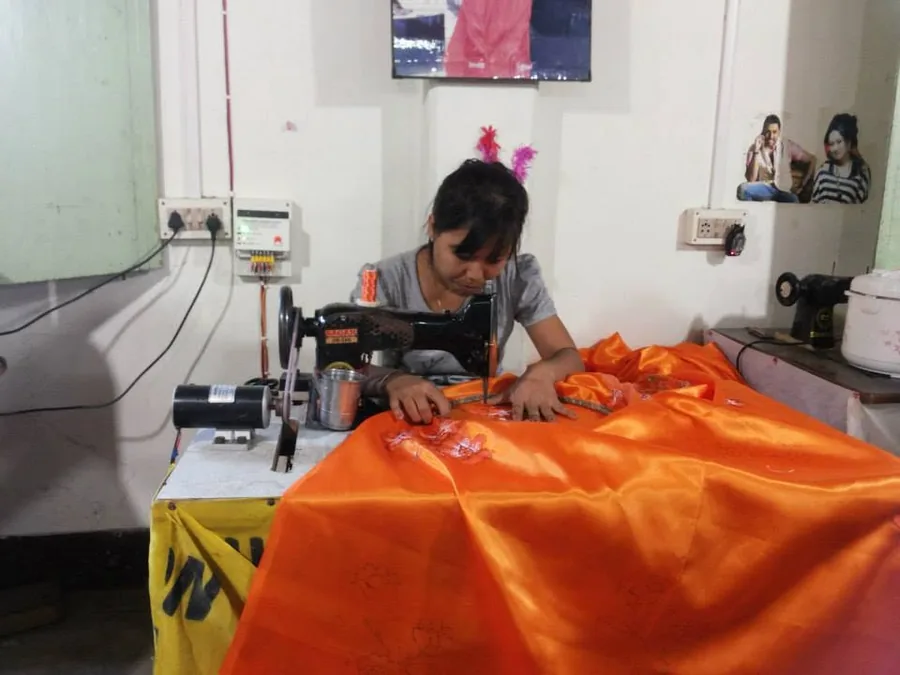 Tailors at work on solar-powered sewing machines in a village workshop