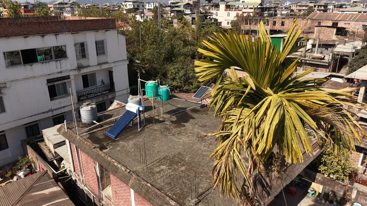Aerial view of a solar water heater and water tanks on an Imphal rooftop